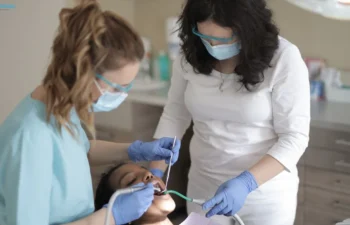 Dental hygienists treating patient with tools in modern clinic